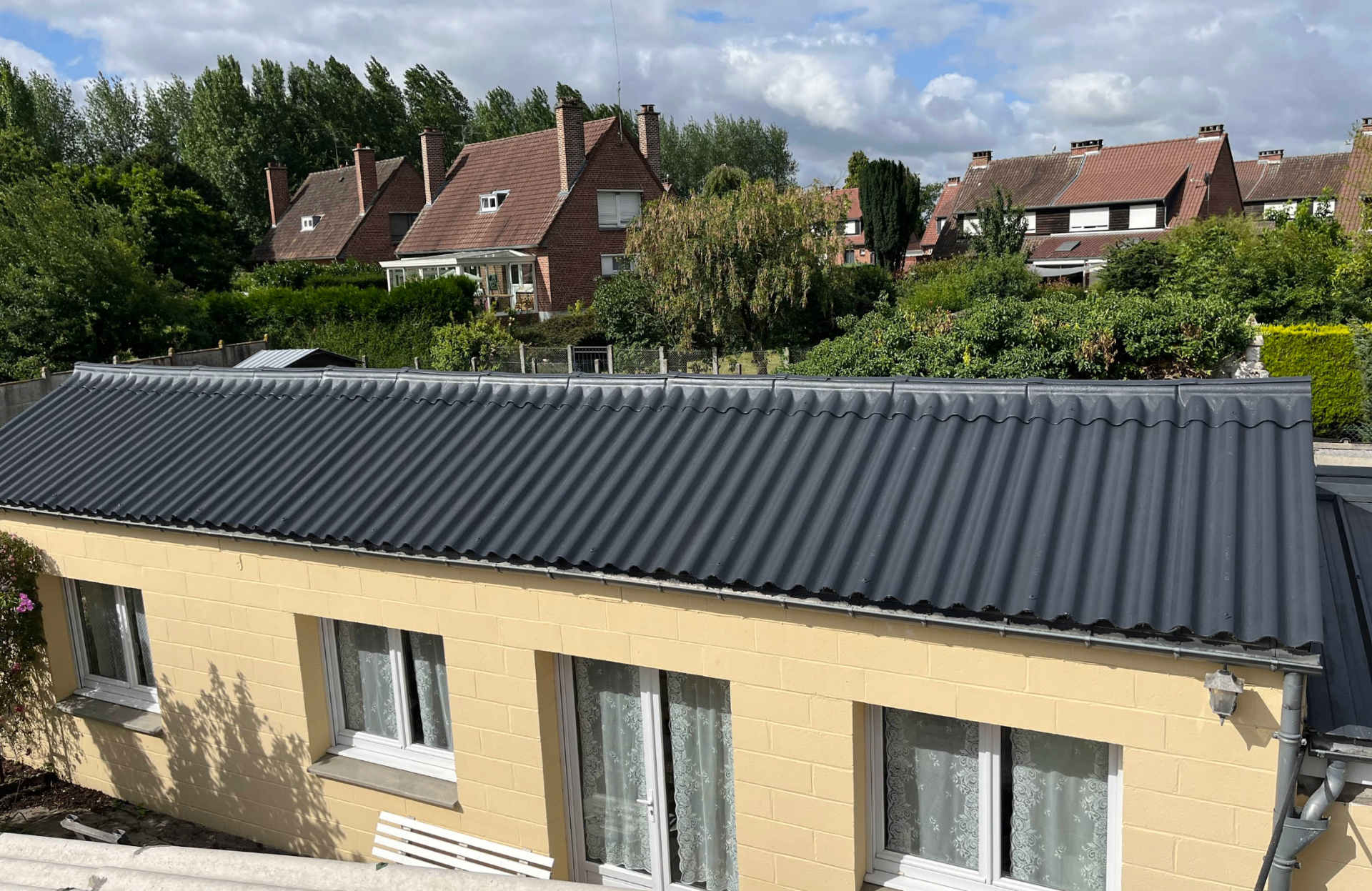 Toiture rénovée en bac acier sombre sur une habitation claire