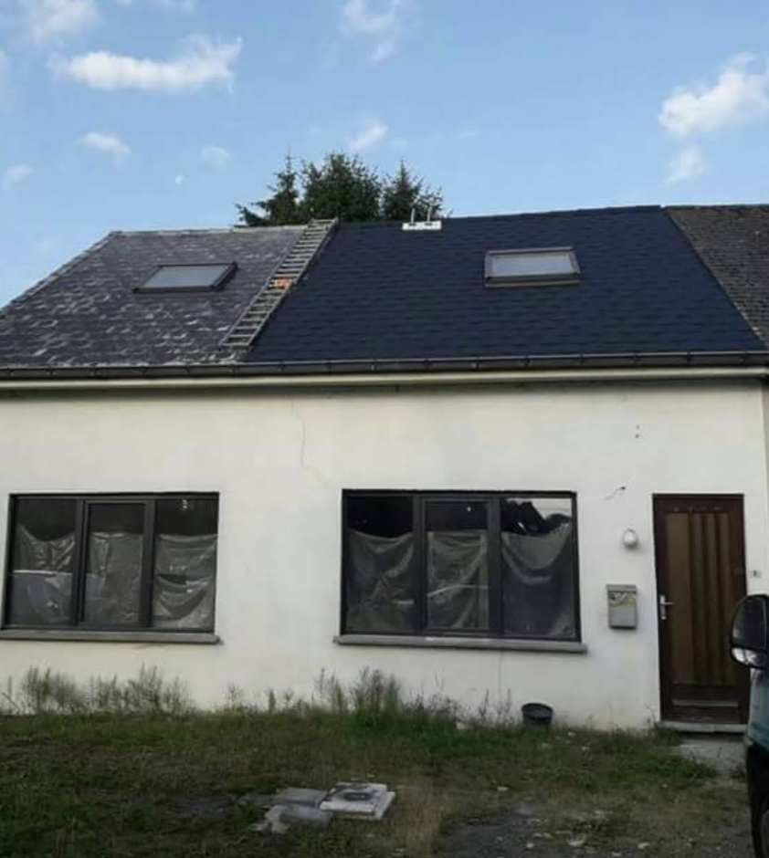 Maison avec toiture rénovée en ardoises foncées et fenêtres de toit